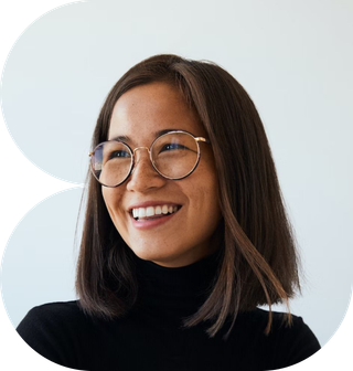 A woman with glasses wearing a black turtleneck sweater, smiling softly at the camera