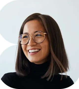 A woman with glasses wearing a black turtleneck sweater, smiling softly at the camera