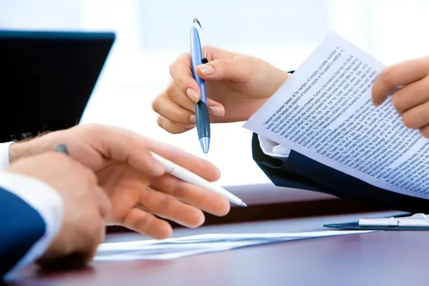 Close-up of hands holding pens and documents during a business meeting, symbolizing collaboration and decision-making