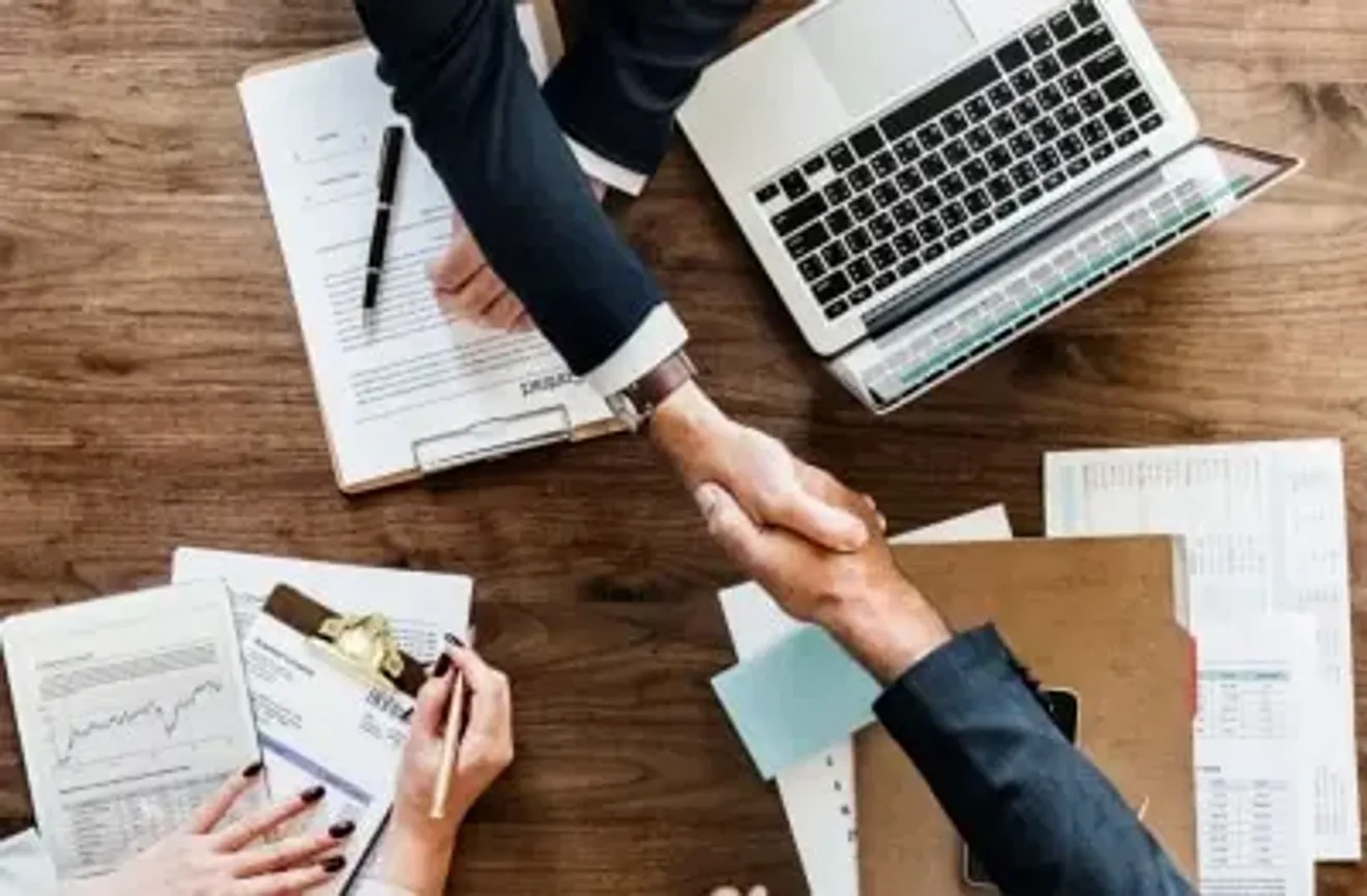Close-up of hands during a business meeting with laptops and printed documents