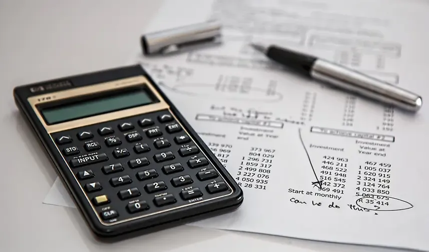 Calculator and pen on top of financial documents, representing calculations and financial planning.