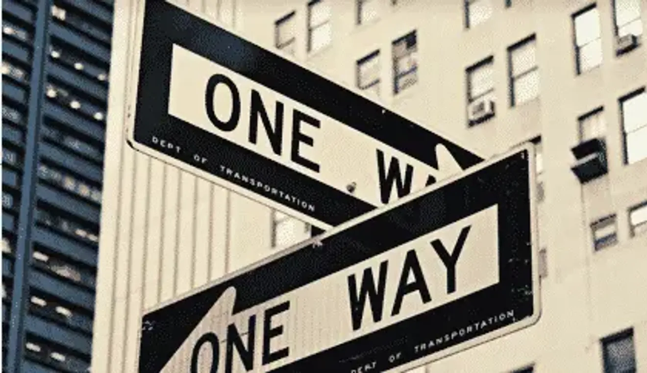 Two intersecting "One Way" street signs in an urban setting, symbolizing limited options or direction related to deportation