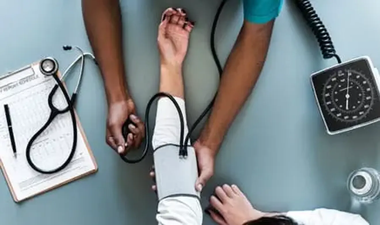 Doctor measuring patient's blood pressure with stethoscope and sphygmomanometer
