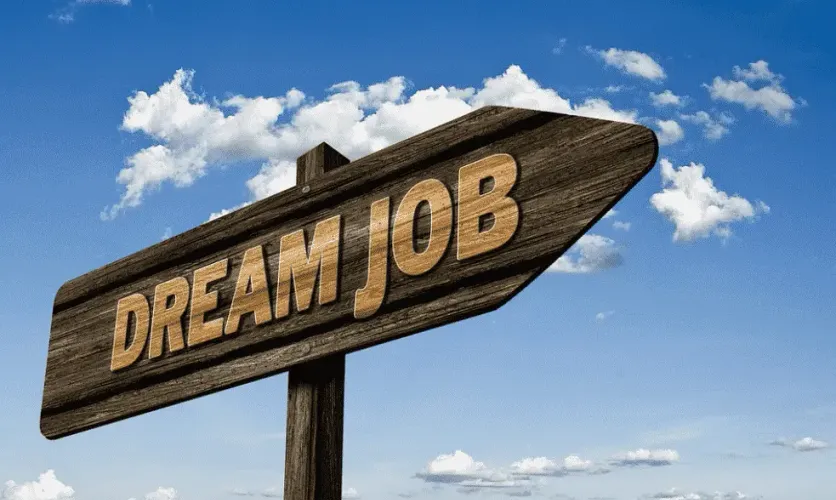 Wooden signpost reading “Dream Job” pointing toward a bright blue sky, symbolizing career aspirations and opportunities