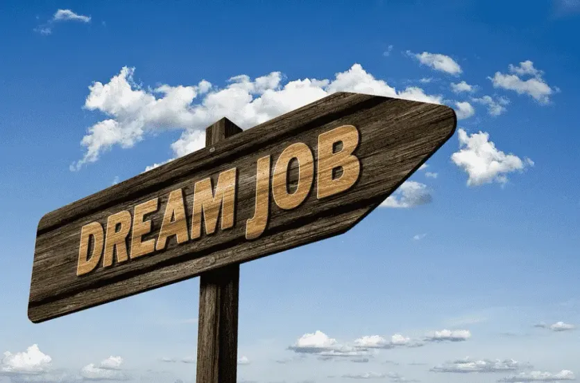 Wooden signpost reading “Dream Job” pointing toward a bright blue sky, symbolizing career aspirations and opportunities
