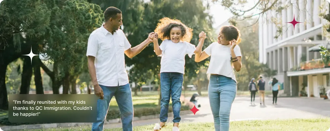 A smiling couple swings their child joyfully between them in a sunlit park, with modern buildings and other people in the background.