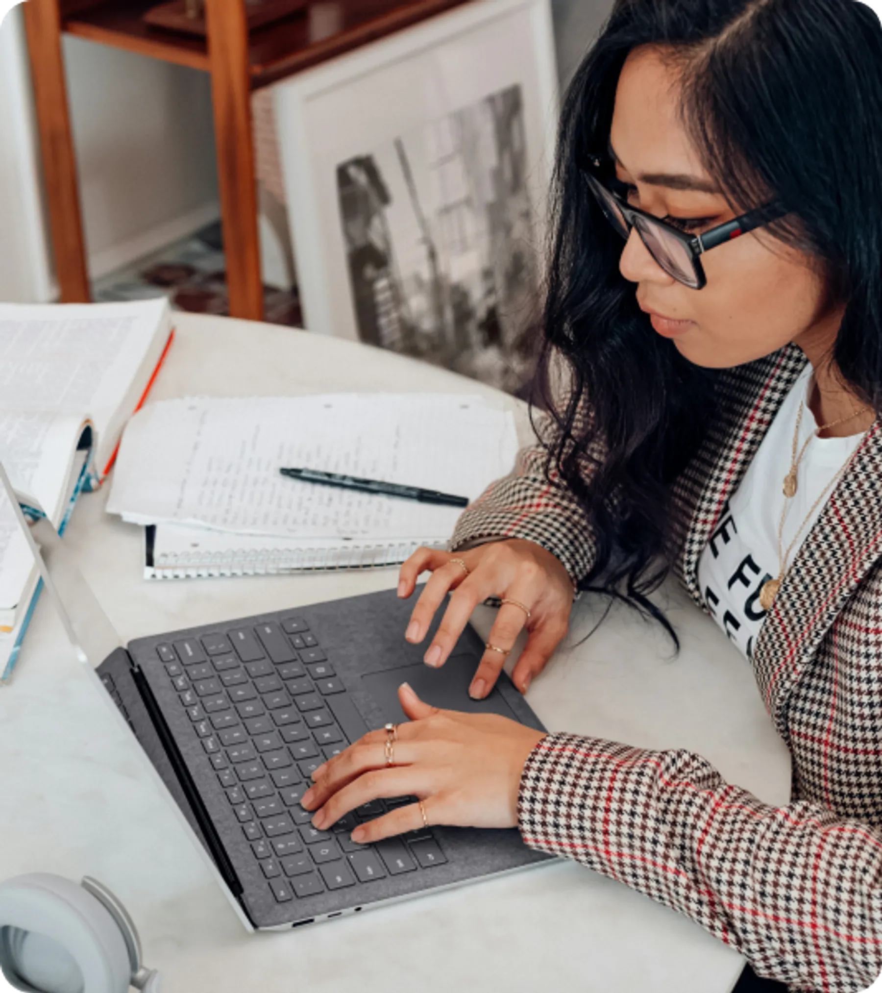 Woman working on laptop with documents and notes, representing service providers applying for Switzerland visa or permit