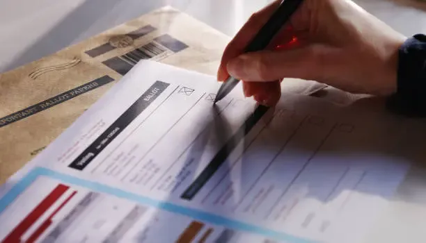 Close-up of a hand filling out a form with a pen next to a package