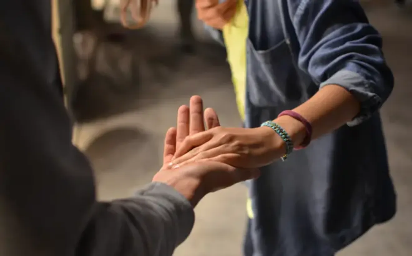 Close-up of two people holding hands, symbolizing support and compassion