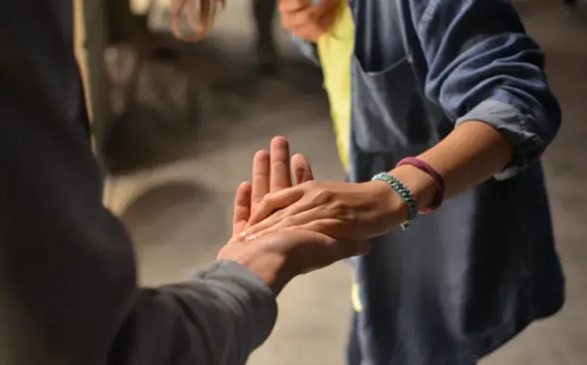 Close-up of two people holding hands, symbolizing support and compassion