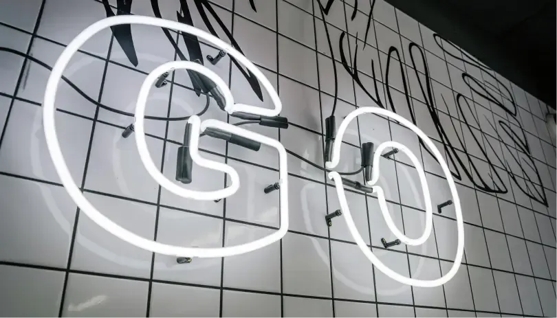 Neon “GO” sign on tiled wall, symbolizing departure or leaving the UK