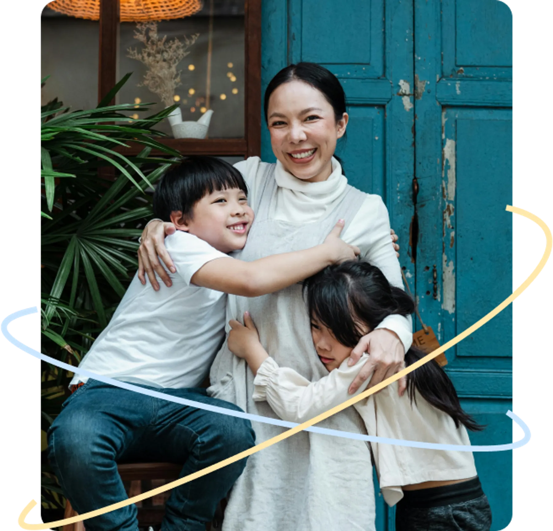 Smiling mother standing in front of a blue door, warmly hugging her two children.