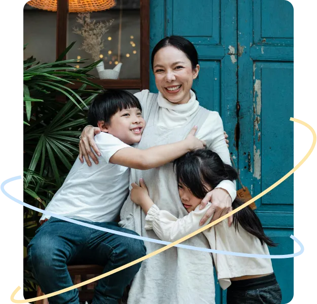 Smiling mother standing in front of a blue door, warmly hugging her two children.
