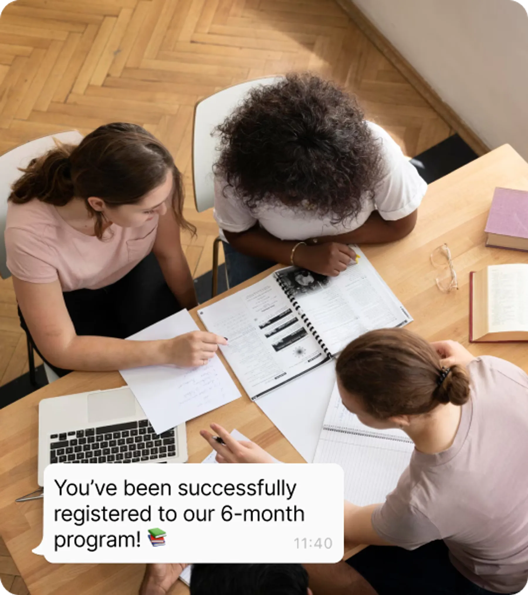 Three students gathered around study materials and a laptop, reviewing an English course curriculum with a visible overlay message confirming registration for a 6-month program.