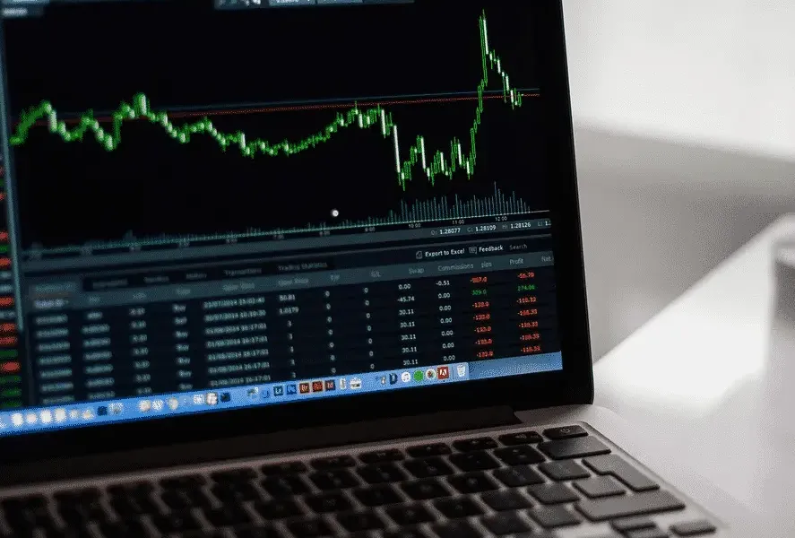 Laptop screen displaying a stock market chart with fluctuating prices and data tables.