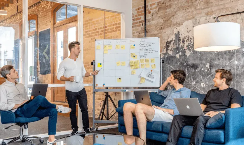Startup team brainstorming around a whiteboard in a modern office setting
