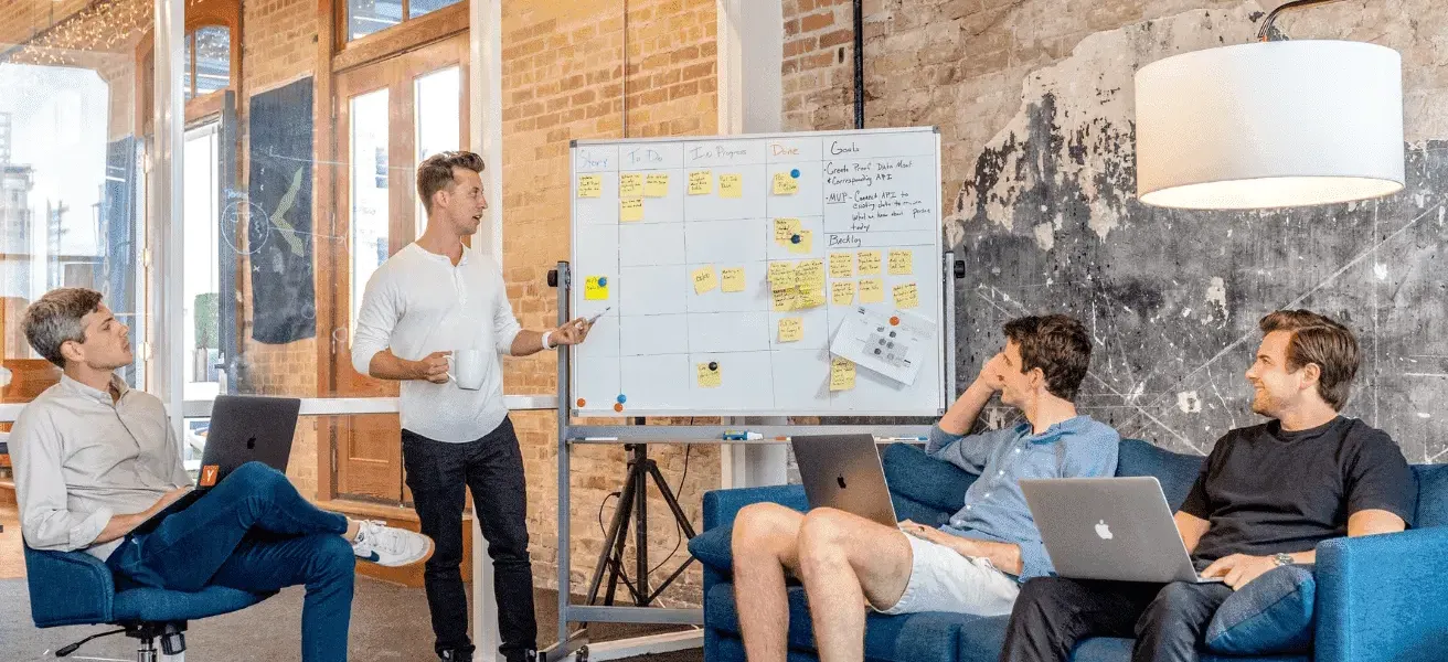Startup team brainstorming around a whiteboard in a modern office setting