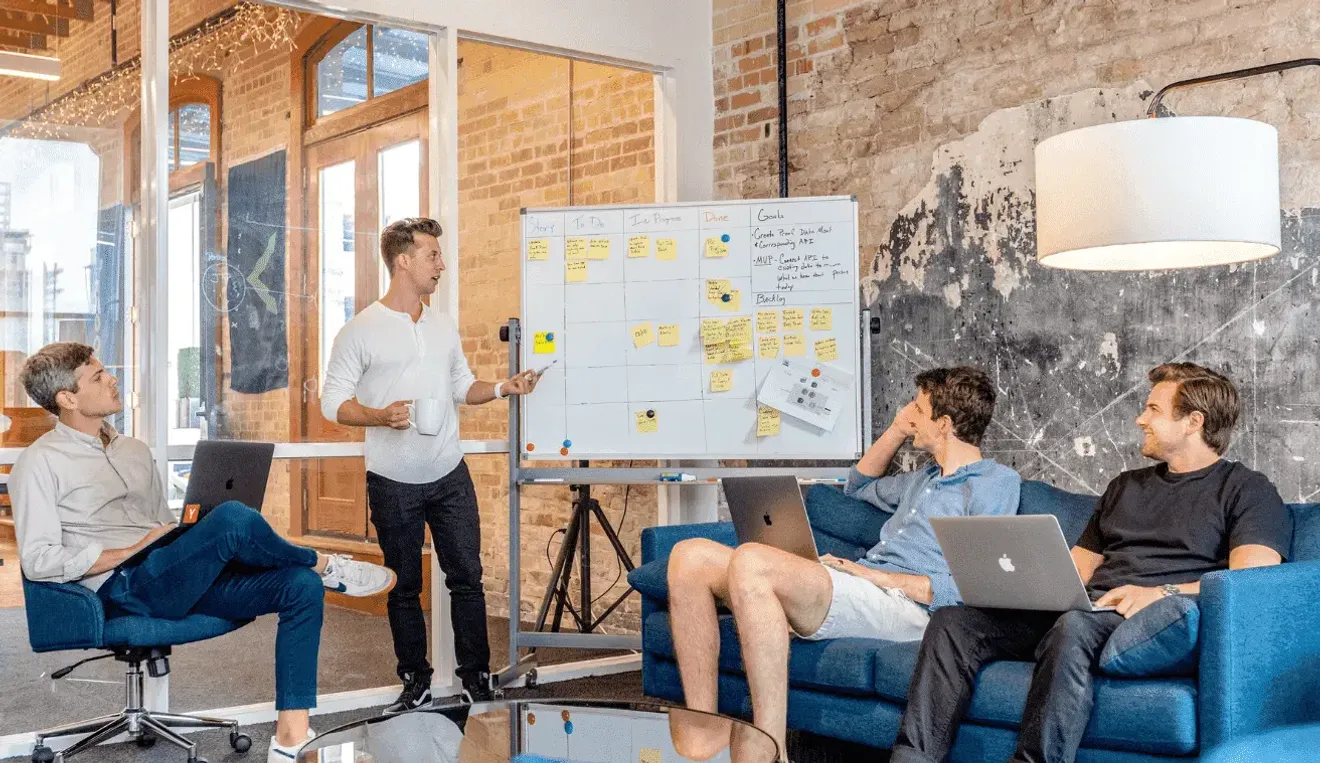Startup team brainstorming around a whiteboard in a modern office setting