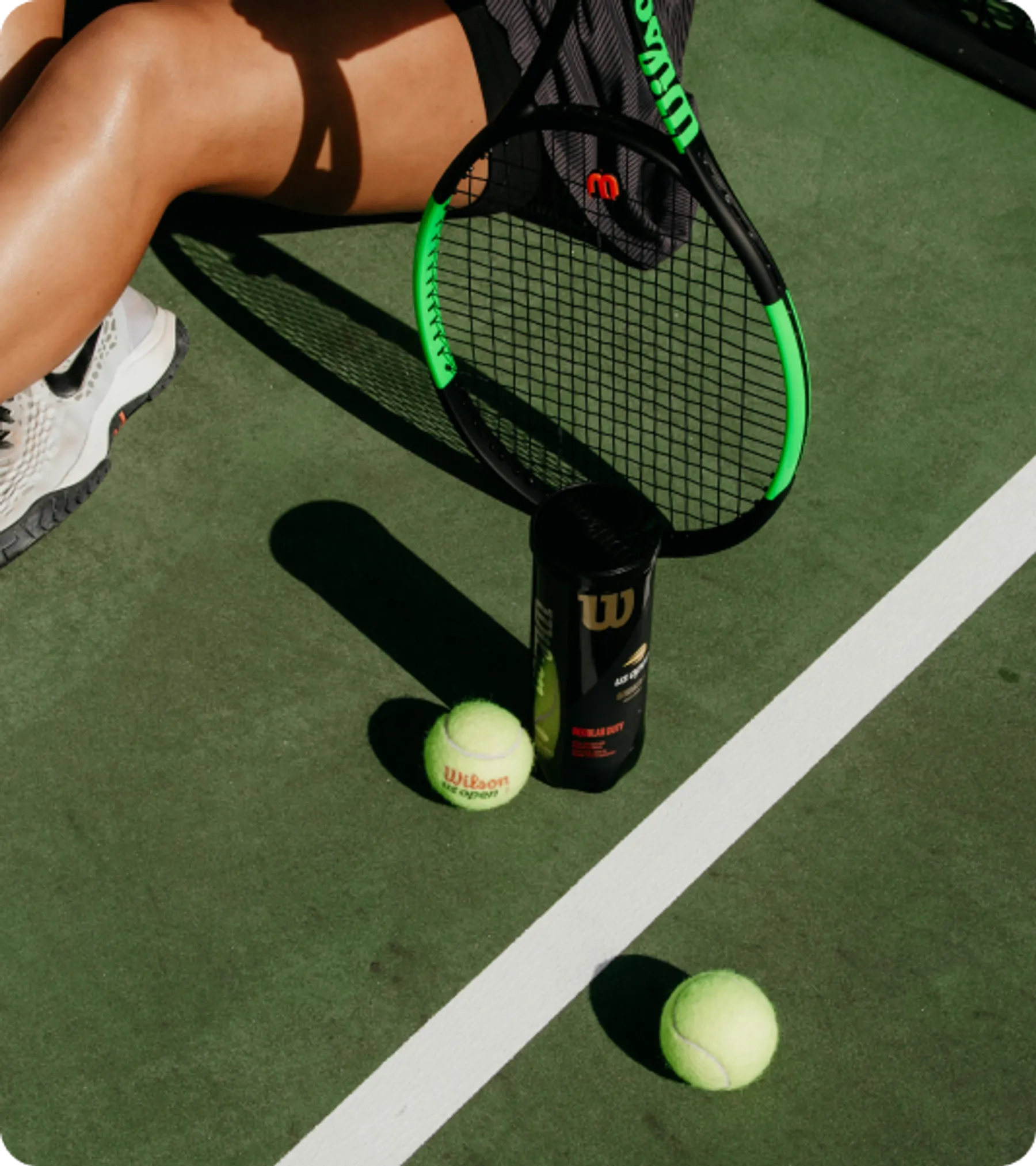 Tennis player with racket and balls on court, symbolizing athletes eligible for the UK International Sportsperson Visa