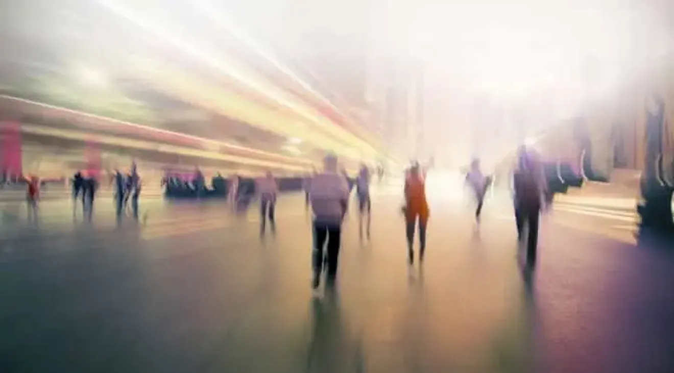 Blurred motion photo of people walking through a modern transit hub, symbolizing travel and immigration movement