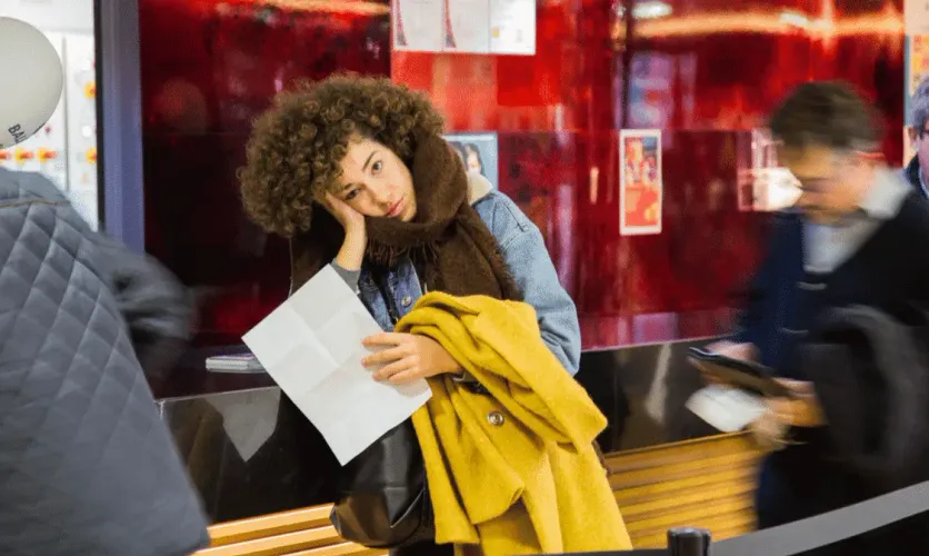 Woman holding passport and immigration documents at a train station, preparing for international travel