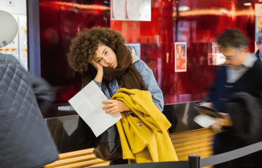 Woman holding passport and immigration documents at a train station, preparing for international travel