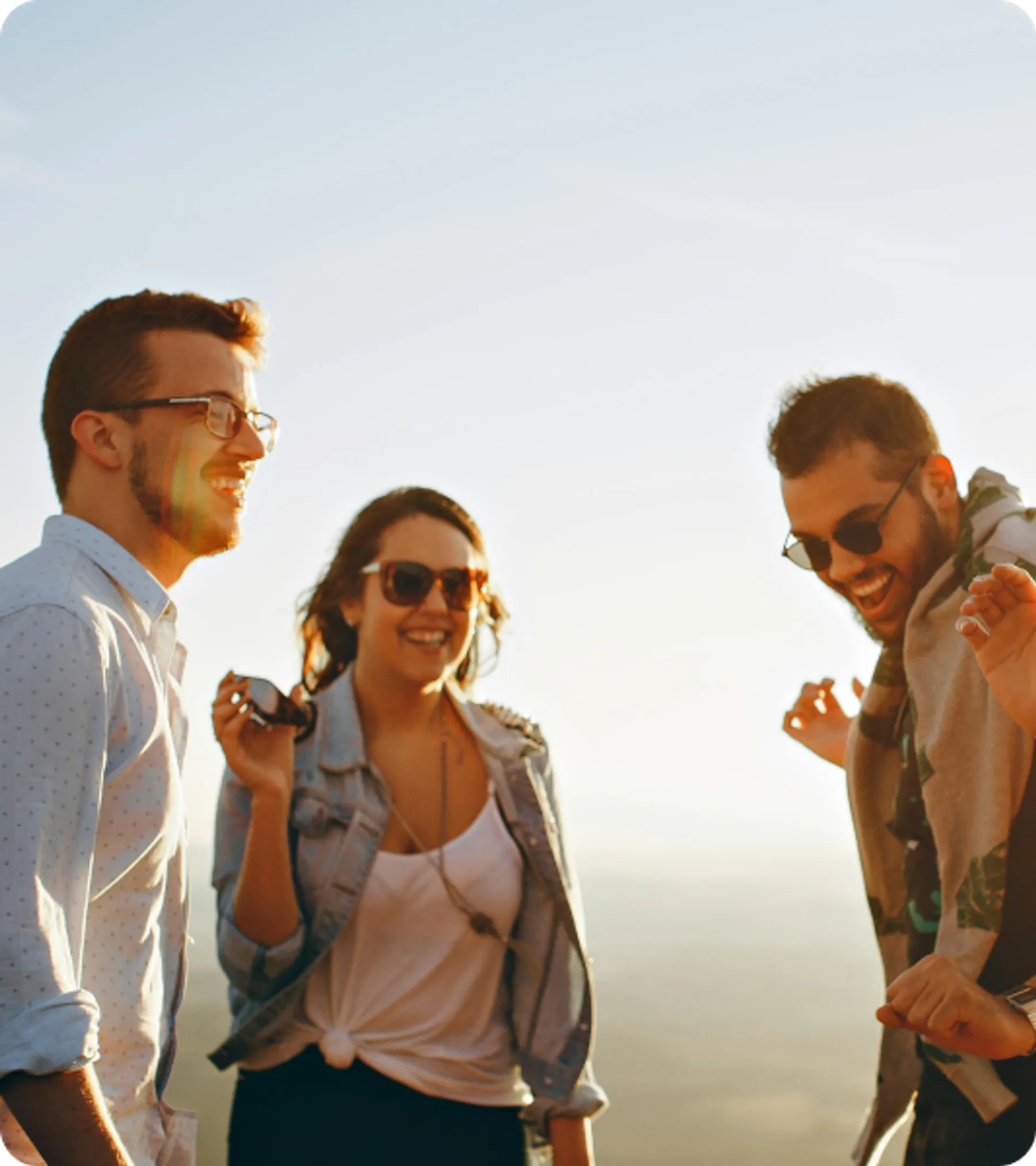 Group of young adults laughing outdoors at sunset, representing participants in the UK Youth Mobility Scheme Visa